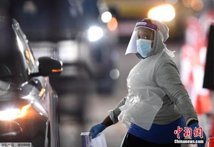 當(dāng)?shù)貢r(shí)間12月18日，英國(guó)政府公布的數(shù)據(jù)顯示，當(dāng)天英國(guó)新增奧密克戎毒株感染病例10059例。鑒于奧密克戎毒株感染病例激增，住院人數(shù)不斷上升，倫敦市長(zhǎng)宣布倫敦進(jìn)入“重大事故”狀態(tài)。圖為倫敦的一個(gè)免下車檢測(cè)中心，一名醫(yī)務(wù)工作者正準(zhǔn)備對(duì)司機(jī)進(jìn)行核酸檢測(cè)。