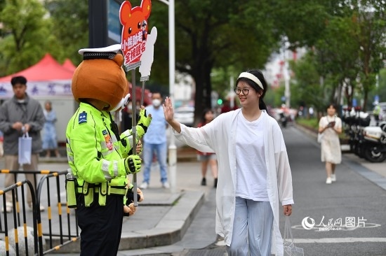 6月7日上午9時(shí)，隨著鈴聲的響起，2023年江西高考正式開(kāi)考，江西省的53.57萬(wàn)考生以縣（區(qū)）為單位隨機(jī)安排在全省256個(gè)考點(diǎn)、18968個(gè)考場(chǎng)參加高考。圖為“小熊交警”和考生擊掌鼓勵(lì)。 人民網(wǎng)記者 時(shí)雨攝