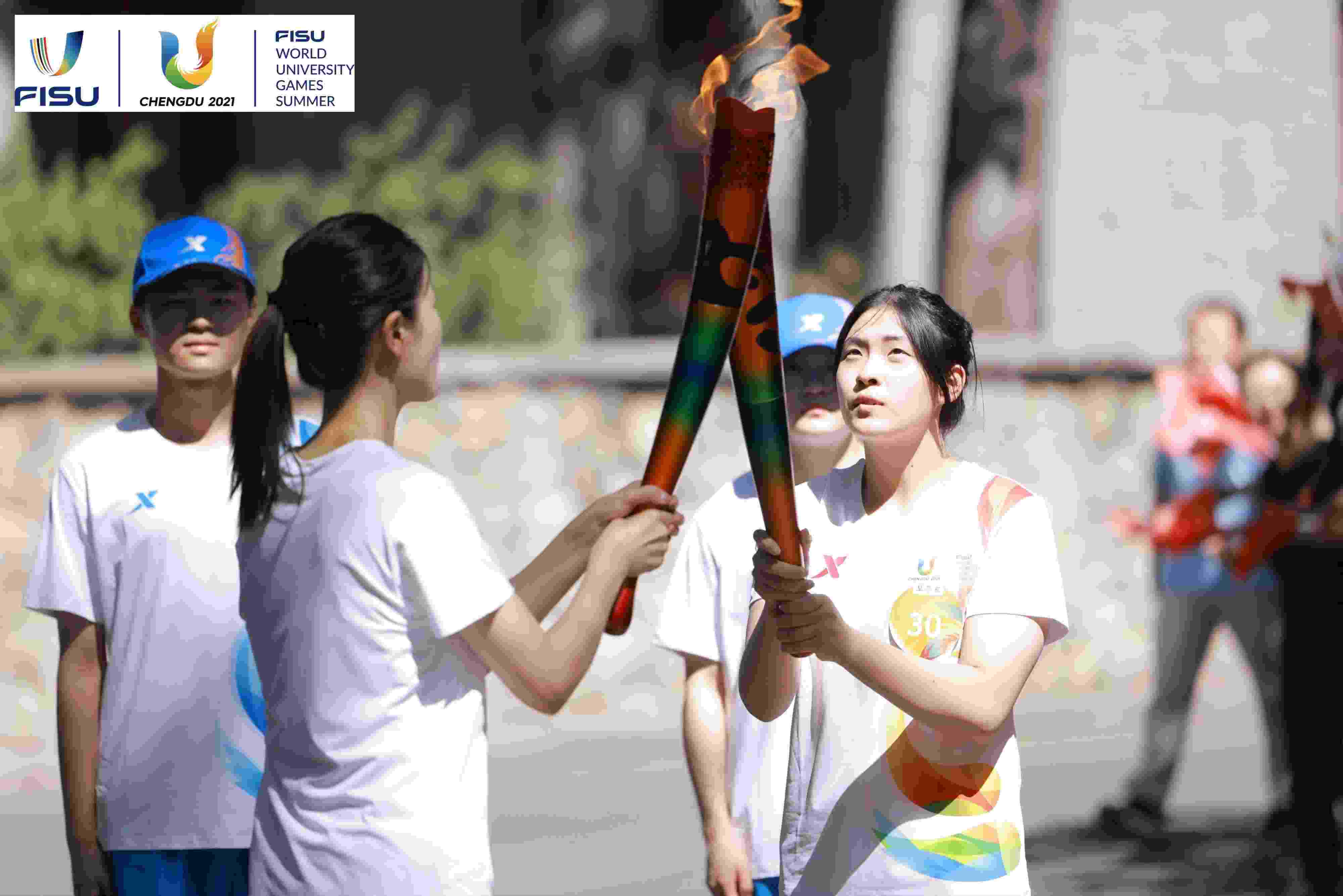 兩名大運(yùn)會(huì)火炬手進(jìn)行火炬?zhèn)鬟f。 圖片來源：成都大運(yùn)會(huì)執(zhí)委會(huì)供圖