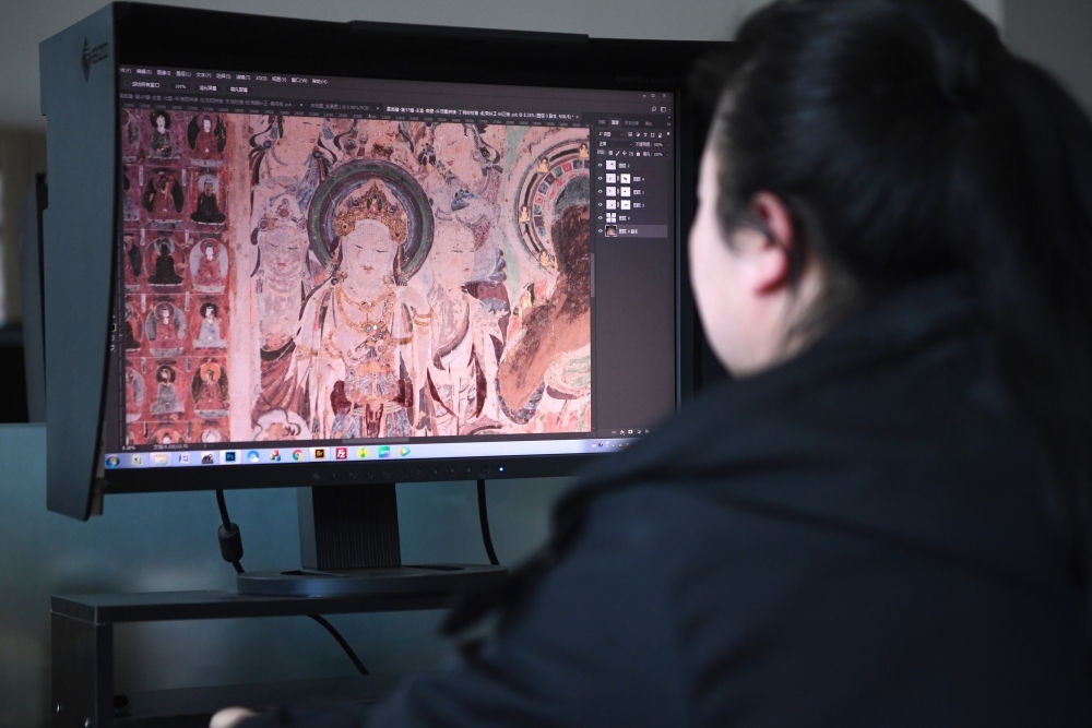 敦煌研究院文物數(shù)字化保護團隊圖像處理人員年海麗在拼接壁畫圖像（2023年4月25日攝）。數(shù)字化探索為莫高窟的保護與傳承開辟了全新路徑，數(shù)字技術讓敦煌文物走出洞窟，跨出國門，走向“永久保存、永續(xù)利用”。新華社記者 陳斌 攝