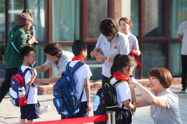 8月30日，雄安史家胡同小學(xué)學(xué)生體驗(yàn)學(xué)校生活。老師為學(xué)生佩戴?；?。