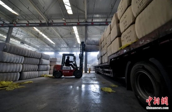 新疆喀什綜合保稅區(qū)，喀什啟路國際貿(mào)易有限公司的倉庫內(nèi)，工人正在裝載從塔吉克斯坦和烏茲別克斯坦進(jìn)口的棉花。劉新攝