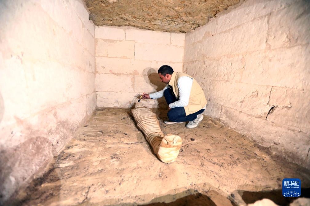 10月15日，在埃及明亞省考古現(xiàn)場，考古人員清理一座石鑿墓中的木乃伊。新華社發(fā)（艾哈邁德·戈馬攝）