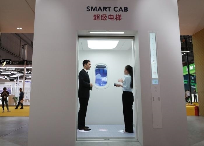 11月5日，工作人員（右）在第六屆進(jìn)博會上向參觀者介紹奧的斯公司全新推出的超級電梯。