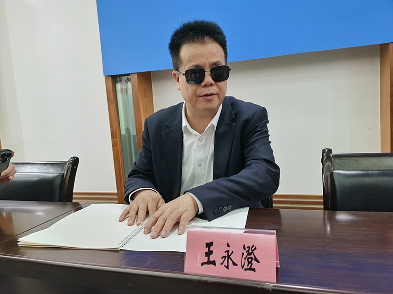 全國(guó)人大代表王永澄正在閱讀盲文版代表建議答復(fù)。本報(bào)記者 張 璁?dāng)z