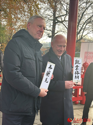 柏林市長韋格納（右）、動物園監(jiān)事會主席布魯克曼（左）手持中國文化中心工作人員現(xiàn)場手書的中文名字。人民網(wǎng)記者 徐馨攝