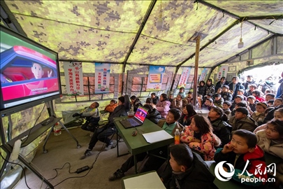 12月22日，在積石山縣大河家鎮(zhèn)大河村安置點(diǎn)，陸軍76集團(tuán)軍某旅搭建的“臨時(shí)學(xué)?！眱?nèi)，小朋友正在看動(dòng)畫片。人民網(wǎng)記者 翁奇羽攝