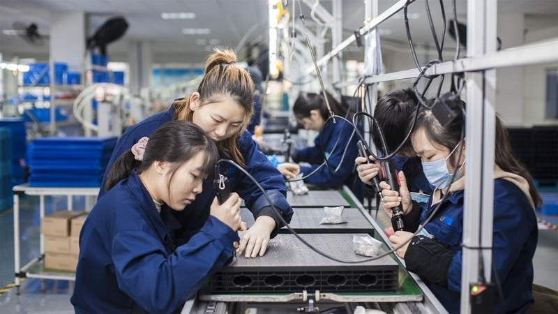 在新亞勝光電的產(chǎn)品線上，工人正進行產(chǎn)品組建和安裝布線。受訪者供圖