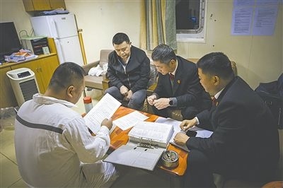 圖②：法官向船長講解相關(guān)法律規(guī)定，查看船舶資料，并與船方辦理扣押船舶的手續(xù)。