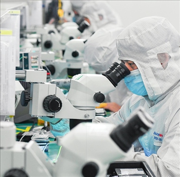 在位于武漢中國光谷的光電器件研發(fā)制造商——武漢光迅科技股份有限公司生產(chǎn)車間內(nèi)，技術(shù)人員在光模塊生產(chǎn)線作業(yè)（2023年4月11日攝）。程敏攝/本刊