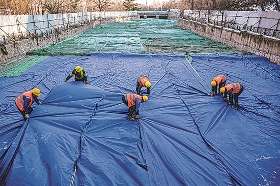 1月3日，房山區(qū)東風(fēng)街道，工人正在修復(fù)的河道內(nèi)給混凝土鋪設(shè)保溫布。