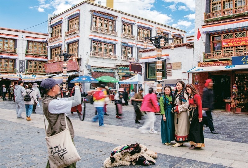 千年八廓街，見證民族團結(jié)。2021年7月，習(xí)近平總書記來到位于西藏拉薩老城區(qū)的八廓街，感慨地說：“千年八廓街，是我們各民族建起來的八廓街。各民族文化在這里交流交往交融，我們中華民族的大家庭在這里其樂融融。”圖為2023年6月13日，游客身著藏裝在八廓街拍照留念。 新華社記者 姜帆/攝