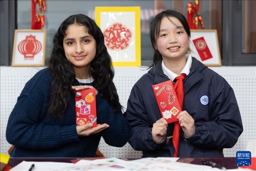 1月28日，美國馬斯卡廷中學學生（左）和復旦大學第二附屬學校學生展示互相送出的寫有寄語祝福的紅包。 新華社記者 王翔 攝