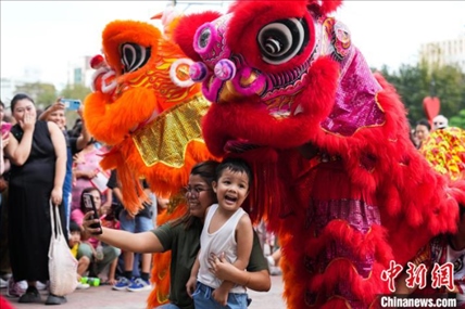 圖為舞獅表演吸引民眾合影。張興龍攝