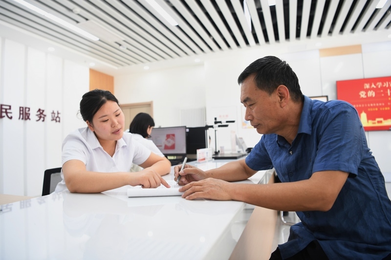 2023年5月23日，河北雄安新區(qū)容東片區(qū)南文營(yíng)社區(qū)居民（右）在社區(qū)便民服務(wù)站辦理業(yè)務(wù)。
