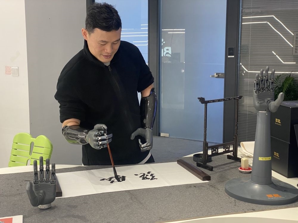 2024年3月29日，在浙江強腦科技有限公司展廳內(nèi)，失去雙手的產(chǎn)品體驗官倪敏成依靠智能仿生手寫毛筆字。新華社記者 魏一駿 攝