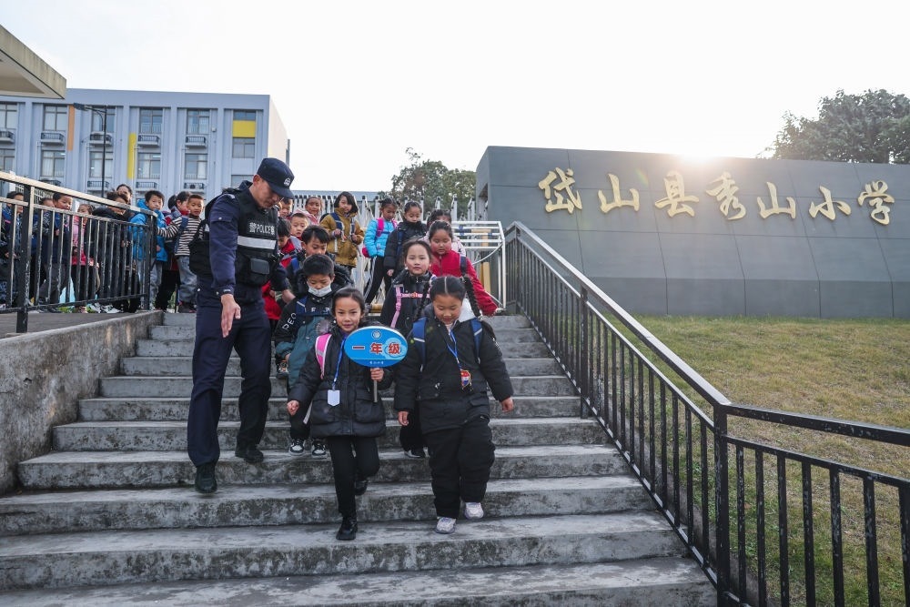 2023年12月20日，秀山派出所民警在秀山小學(xué)放學(xué)時(shí)間參與“護(hù)學(xué)崗”維持秩序，同時(shí)接獨(dú)自放學(xué)的學(xué)生去“民生小鋪”。浙江省舟山市岱山縣公安局秀山派出所聯(lián)合鄉(xiāng)鎮(zhèn)、社區(qū)成立“民生小鋪”，為當(dāng)?shù)鼐用?、外?lái)務(wù)工人員及其子女等服務(wù)，協(xié)助解決外來(lái)務(wù)工人員在工作、生活等方面的矛盾和問(wèn)題，助力鄉(xiāng)鎮(zhèn)基層治理。新華社記者 徐昱 攝