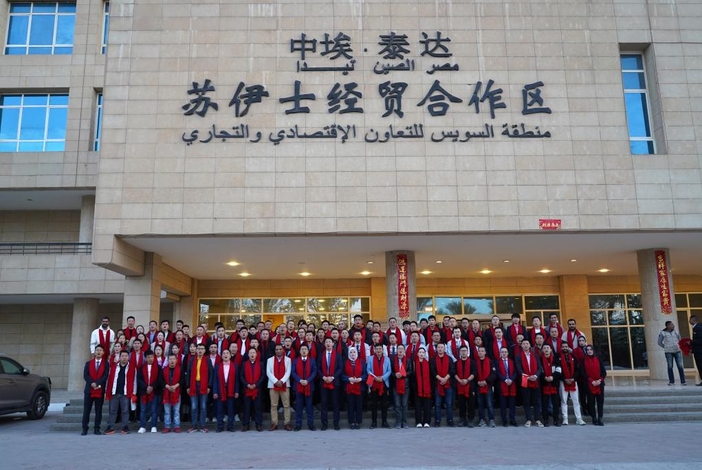 2024年2月11日，在位于埃及蘇伊士省的中?！ぬ┻_(dá)蘇伊士經(jīng)貿(mào)合作區(qū)，中埃員工在合作區(qū)辦公大樓前合影拜年。新華社發(fā)（泰達(dá)合作區(qū)供圖）