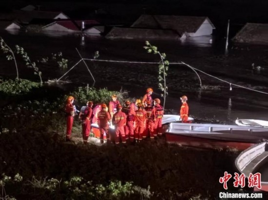  7月6日凌晨3時，在湖南岳陽華容縣團(tuán)洲垸洞庭湖一線堤防，救援人員剛剛完成一次救援任務(wù)，遠(yuǎn)處是被淹的民房。中新社記者 白祖偕 攝