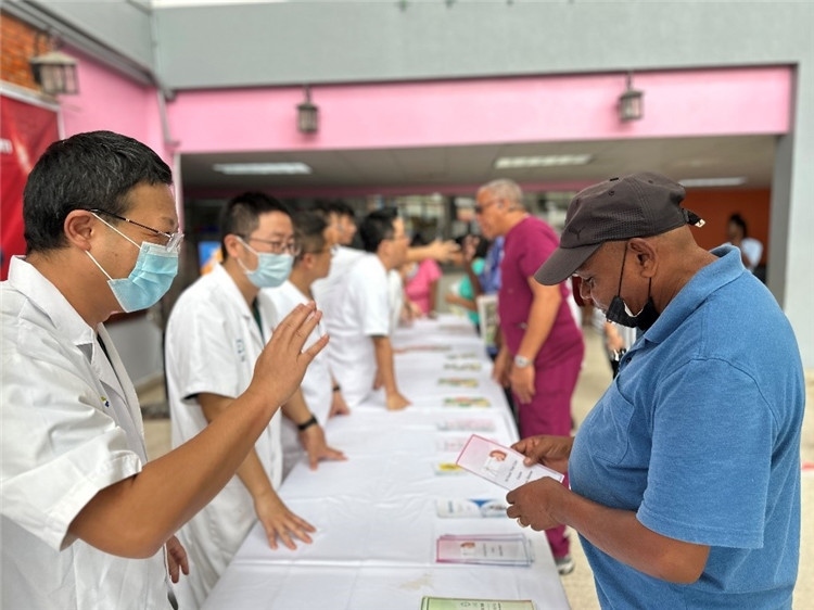 援圭醫(yī)療隊(duì)隊(duì)員們?cè)趩?dòng)儀式上為當(dāng)?shù)孛癖姺职l(fā)宣傳手冊(cè)。中國援助圭亞那醫(yī)療隊(duì)供圖