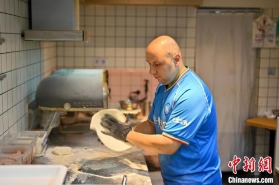 近日，韋榮耀在自家披薩小店內忙活。俞靖 攝