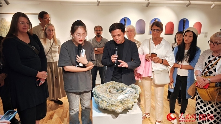 參展人、景德鎮(zhèn)陶瓷大學(xué)設(shè)計(jì)藝術(shù)學(xué)院副院長(zhǎng)余劍峰（中）向來(lái)賓介紹參展作品。人民網(wǎng)記者 殷淼攝