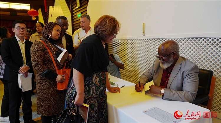 譚哲理在活動現(xiàn)場簽名贈書。人民網(wǎng) 劉暢攝