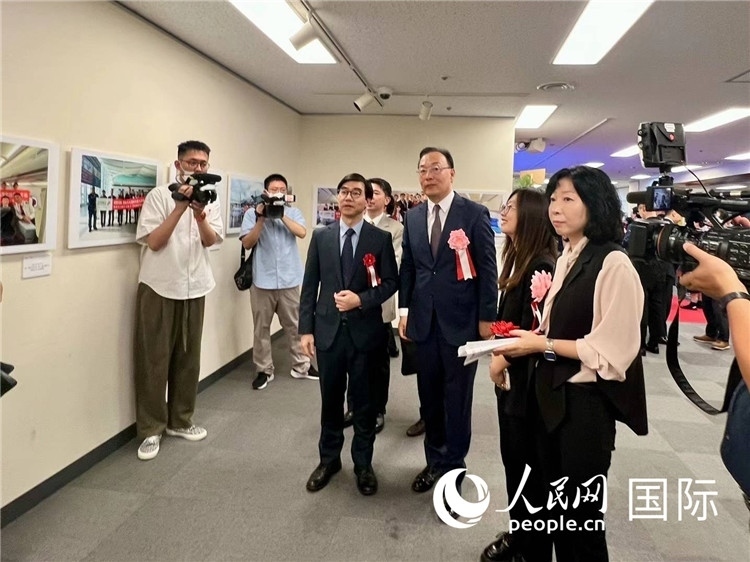 中國國際航空日韓地區(qū)支社支社長馮力為中國駐日本大使館臨時(shí)代辦施泳等嘉賓介紹展出圖片。人民網(wǎng) 許可攝