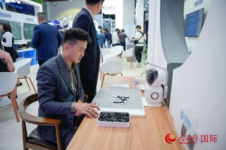 觀眾在中國移動國際有限公司展臺體驗智慧圍棋機器人。人民網(wǎng) 塔里克·易卜拉欣攝