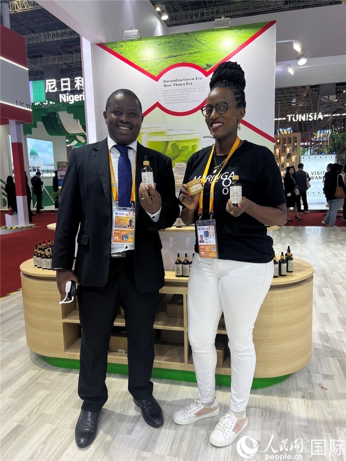 6月6日，布隆迪駐華大使館一等參贊布利馬索·阿爾弗雷德 (左，Bulimaso Alfred) 和參展商卡馬里扎·埃斯特拉 (Kamariza Estella) 在第七屆中國國際進(jìn)口博覽會(huì)布隆迪館展示當(dāng)?shù)厣a(chǎn)的辣木油。（人民網(wǎng) 艾里士 攝）