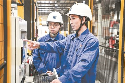 在廣西柳工機(jī)械股份有限公司生產(chǎn)車間內(nèi)，一名高級技師（右）給徒弟講解數(shù)控設(shè)備操作細(xì)節(jié)。新華社記者 曹祎銘攝