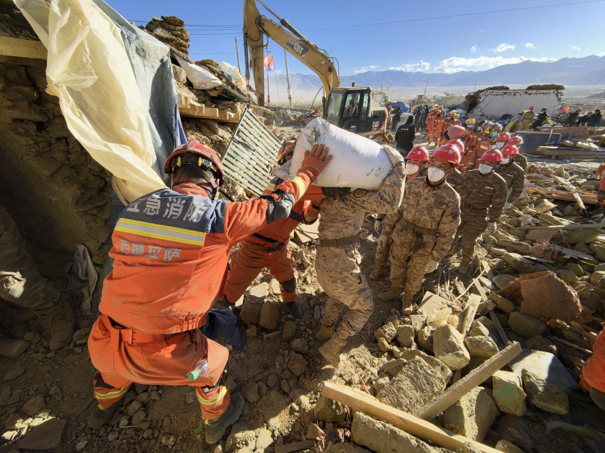 1月11日，定日縣長(zhǎng)所鄉(xiāng)古榮村，應(yīng)急消防等救援人員排隊(duì)接力搶運(yùn)掩埋在倒塌房屋下的群眾財(cái)物。人民日?qǐng)?bào)記者楊翹楚攝