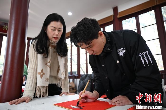 1月20日，外籍留學(xué)生在西泠印社社員李硯指導(dǎo)下寫福。當(dāng)日，來自巴西、馬來西亞、加納、哈薩克斯坦的外籍留學(xué)生在浙江杭州西泠印社體驗福貼、春聯(lián)和篆刻，感受古老的中國傳統(tǒng)文化。中新社記者 王剛 攝