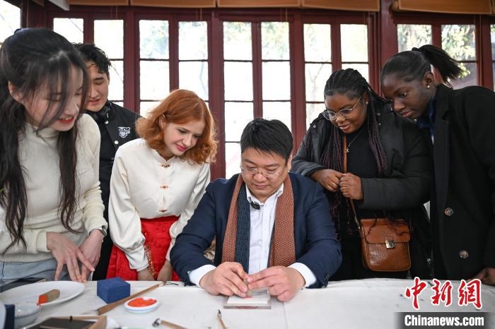 1月20日，篆刻家王臻向外籍留學(xué)生展示篆刻印章。當(dāng)日，來自巴西、馬來西亞、加納、哈薩克斯坦的外籍留學(xué)生在浙江杭州西泠印社體驗福貼、春聯(lián)和篆刻，感受古老的中國傳統(tǒng)文化。中新社記者 王剛 攝