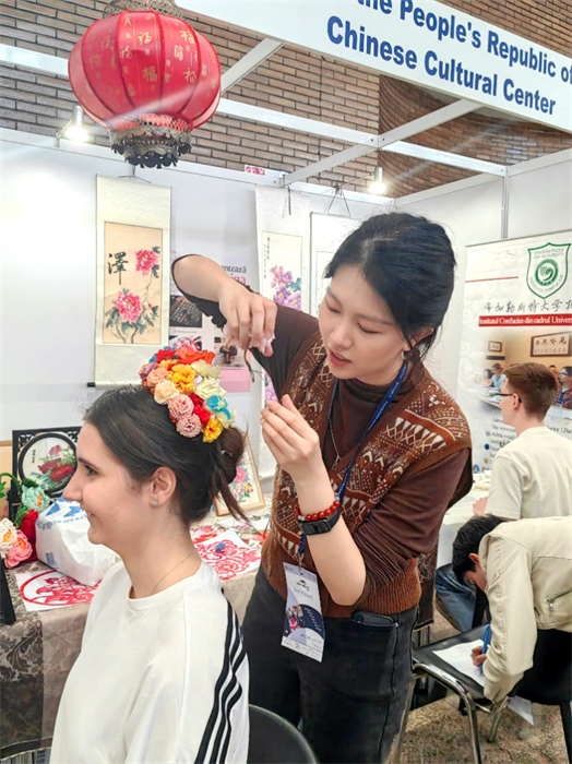 展覽正值羅馬尼亞迎春花節(jié)，國際中文教師志愿者潘婧穎向游客們介紹了國家非物質(zhì)文化遺產(chǎn)——福建泉州的簪花文化。布加勒斯特大學孔子學院供圖。