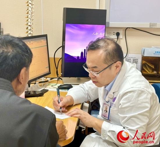 路桂軍接診時(shí)為患者寫下用藥提示。人民網(wǎng)記者 金慧慧攝