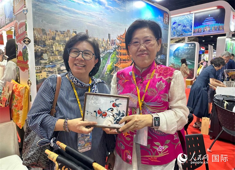 中國“大冶刺繡”傳承人劉小紅（右）參加泰國國際旅游展，向觀眾介紹中國非遺刺繡針法。人民網(wǎng)記者 簡承淵攝